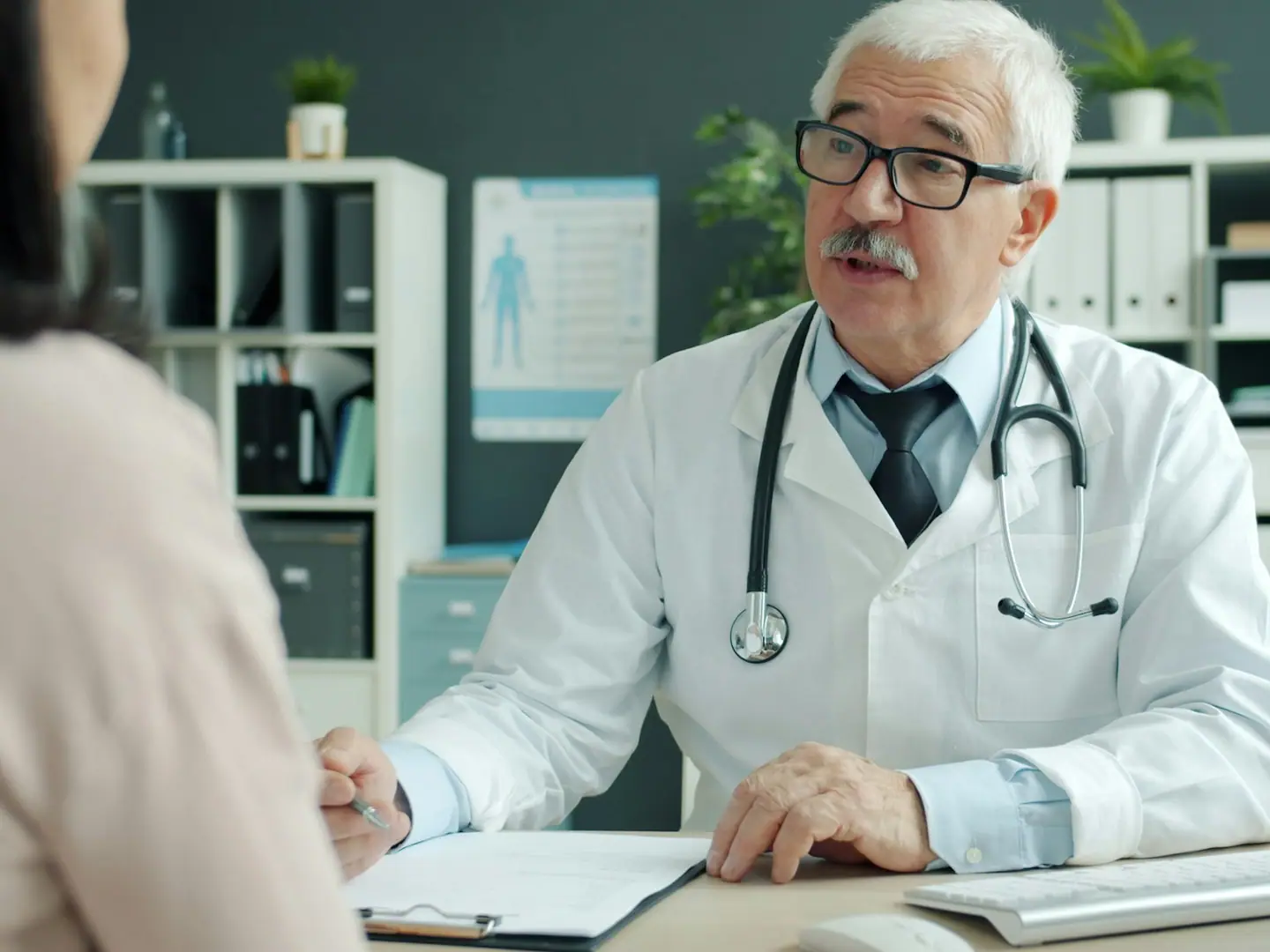 A doctor talking with a patient across the desk in a clinic