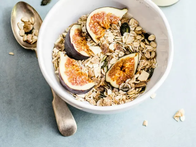 A bowl of oats with figs and seeds, and a bottle of milk