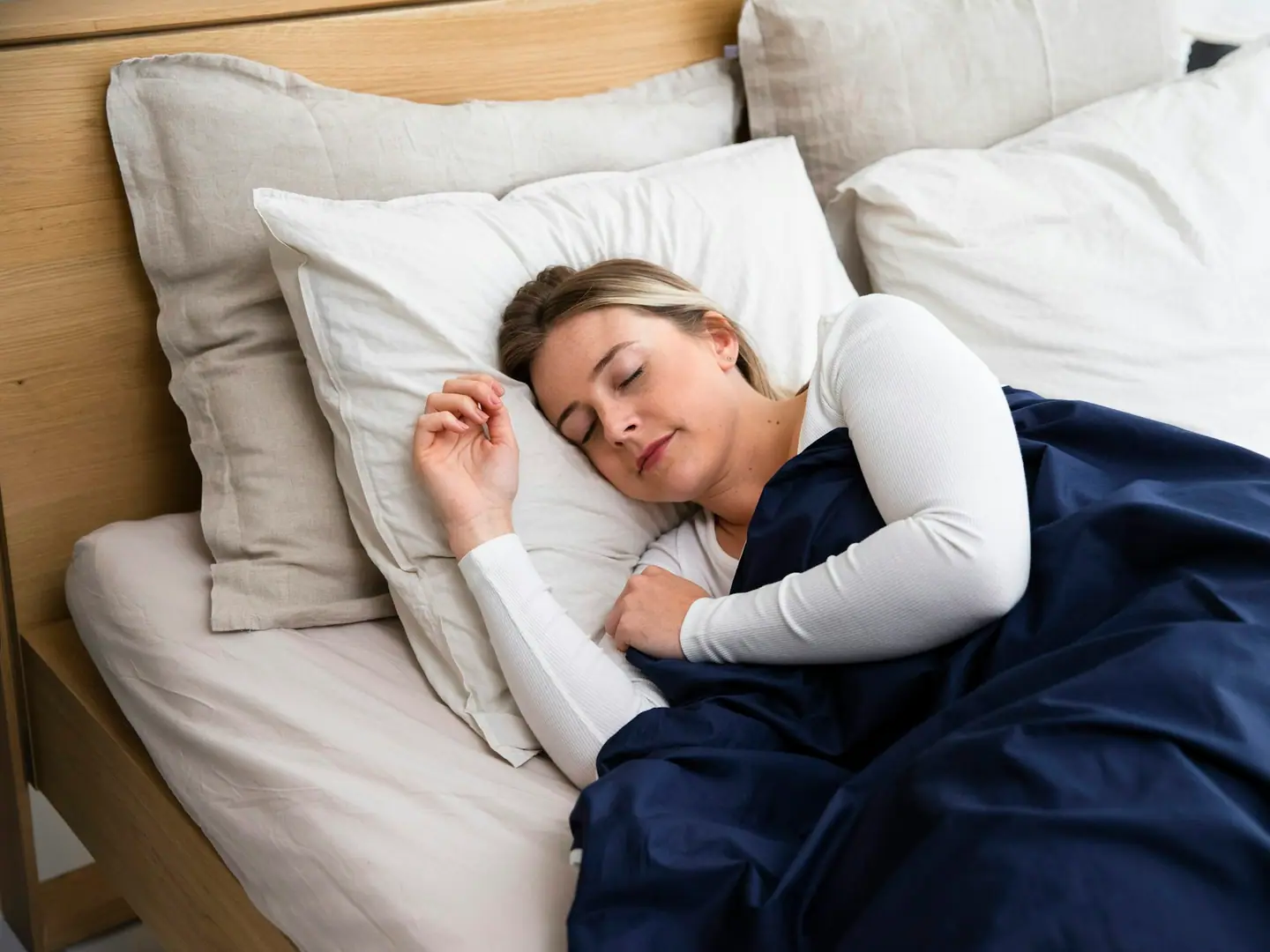 A woman sleeping peacefully under a blue blanket